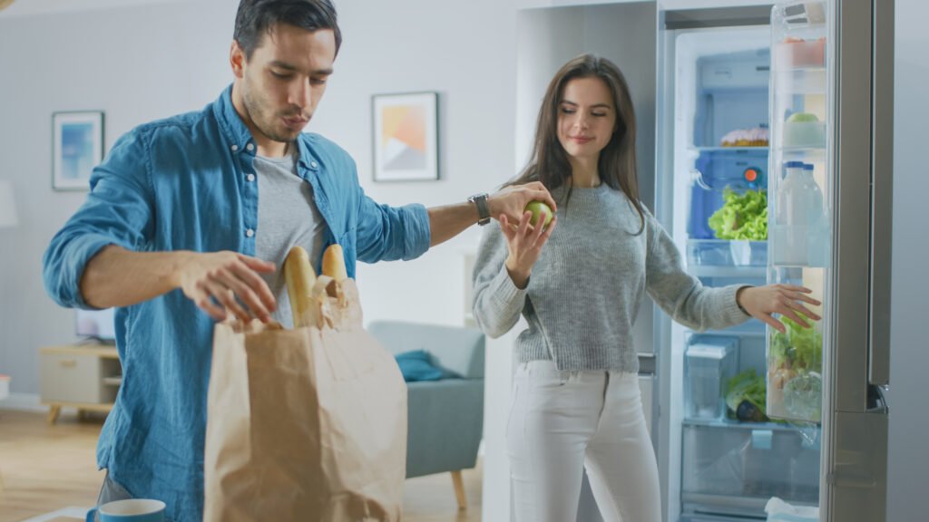 ζευγάρι γεμίζει το ψυγείο με ψώνια